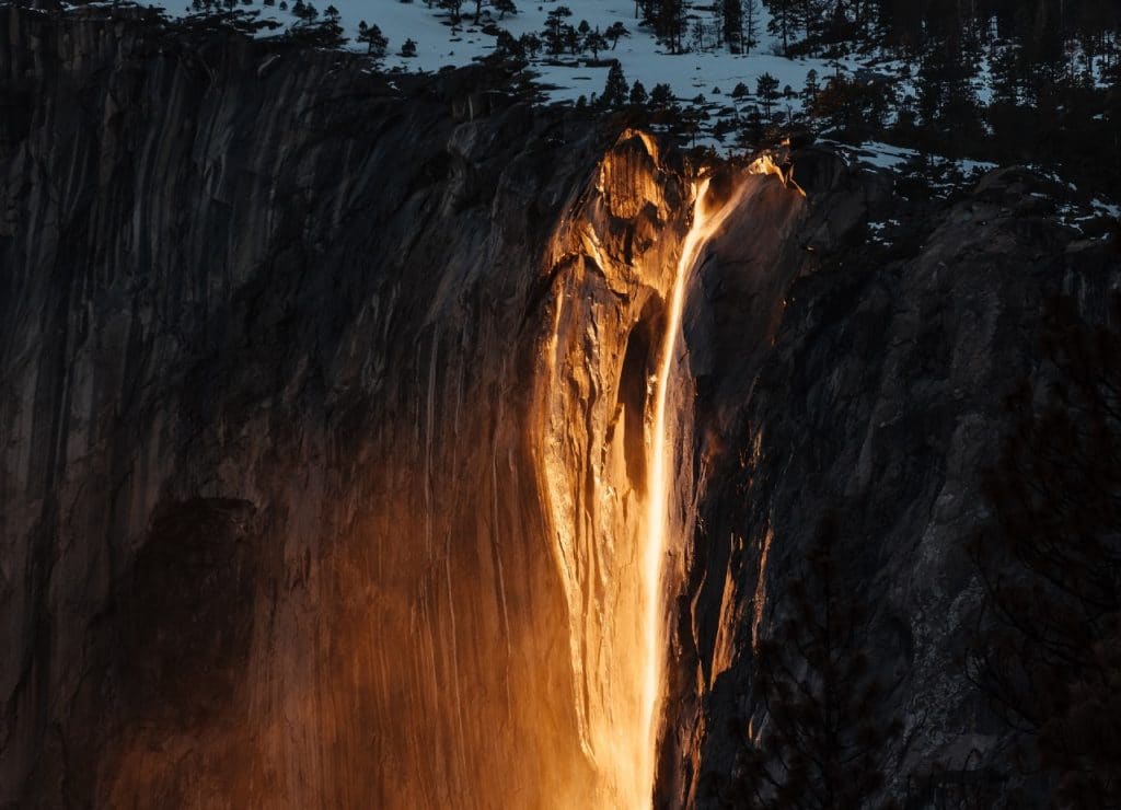 Yosemite's glowing Firefall cascades down from a snowcapped ledge.