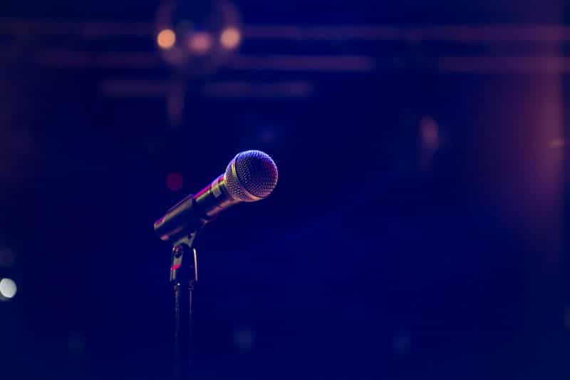 A microphone stands alone in a dark hazy room.