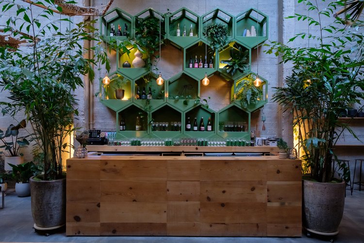 Wine bar with green hexagonal wall-mounted shelf and wooden bar at Arcana, San Francisco