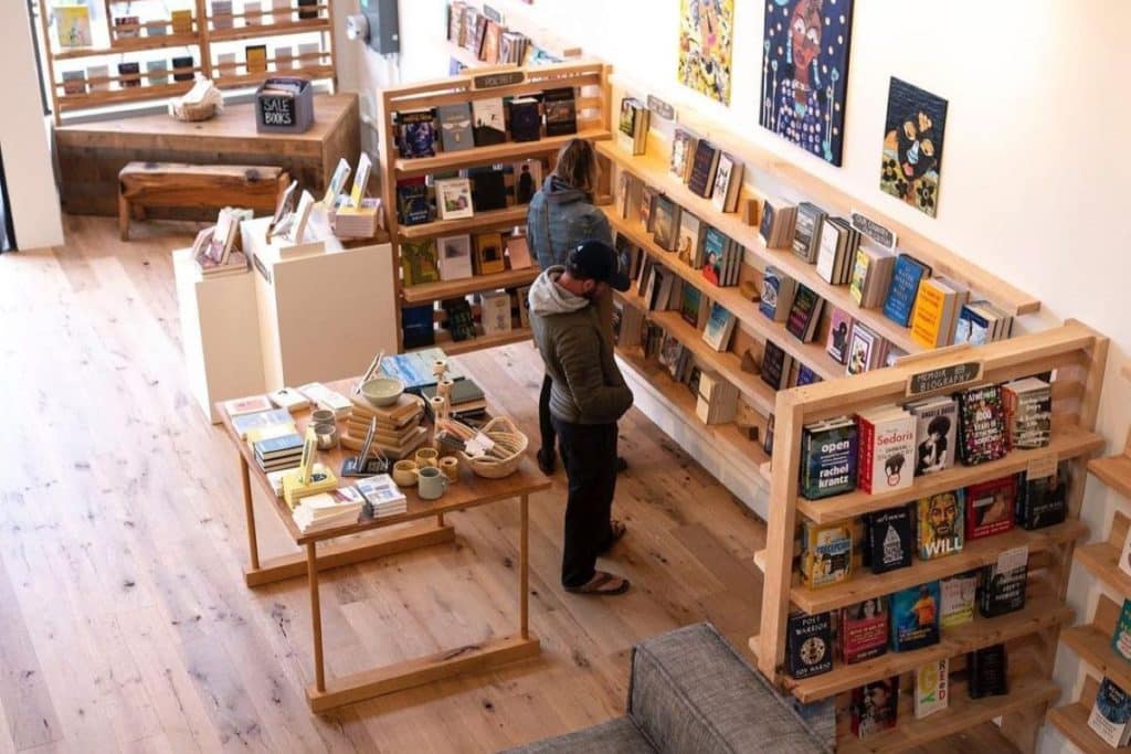 Two people look at book shelves in an open-concept luminous bookstore.