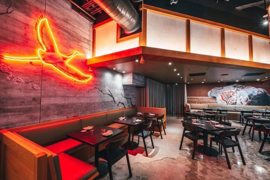 Dining area at Pabu with neon red bird outline on the wall and sleek industrial design