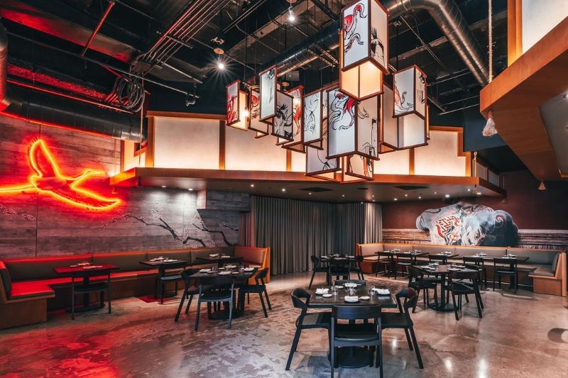 Dining area at Pabu with neon red bird outline on the wall and sleek industrial design