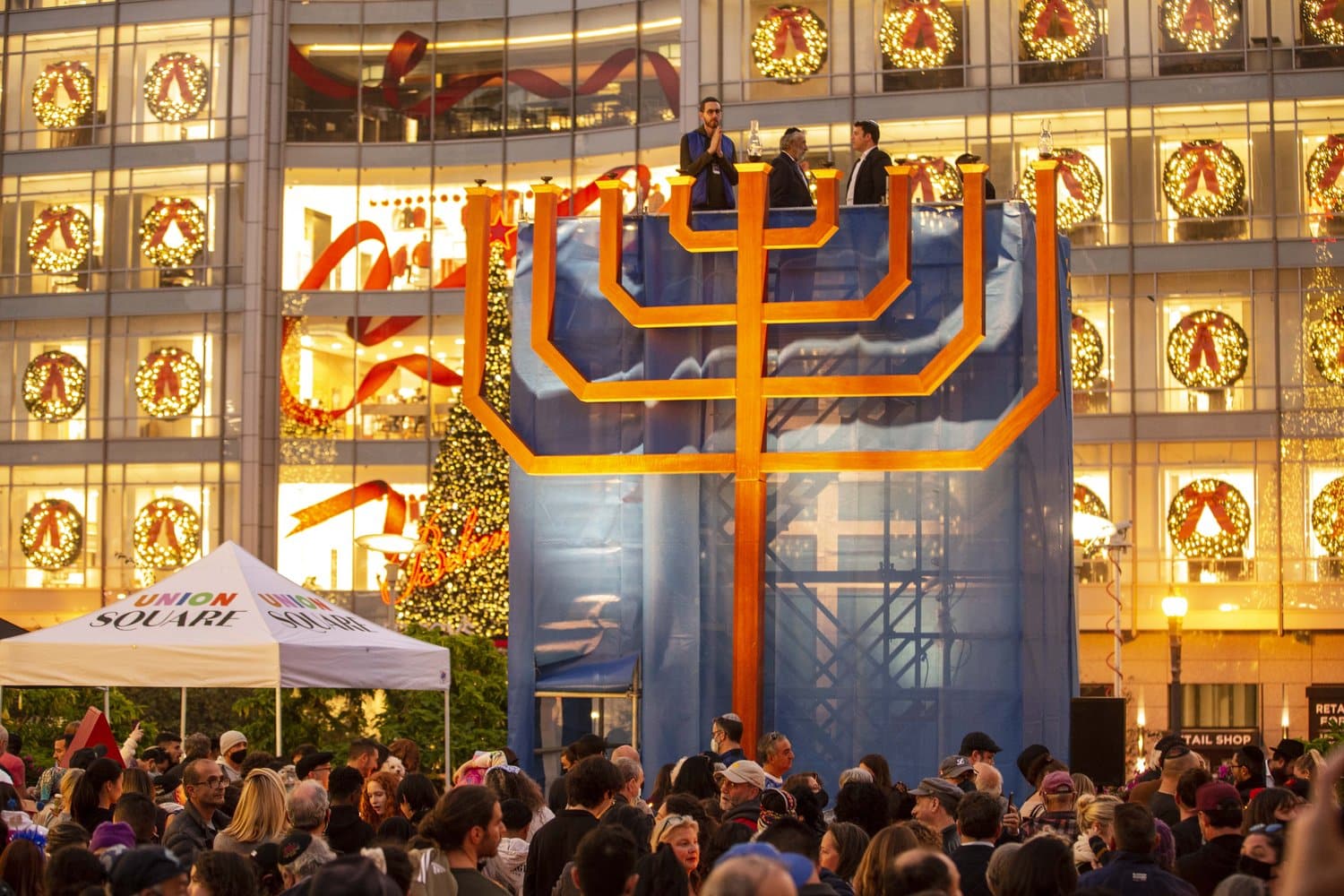 A 25-foot-tall wooden menorah amidst a crowd of people.