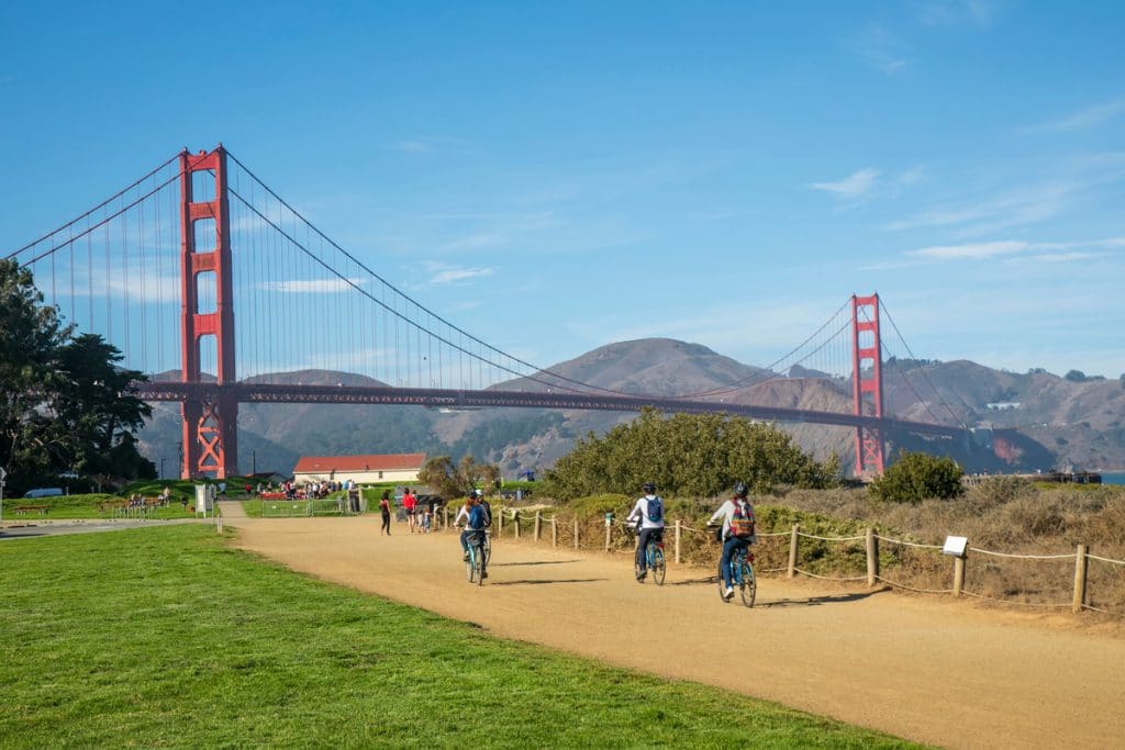 People ride bikes on a path near the Golden Gate Bridge.