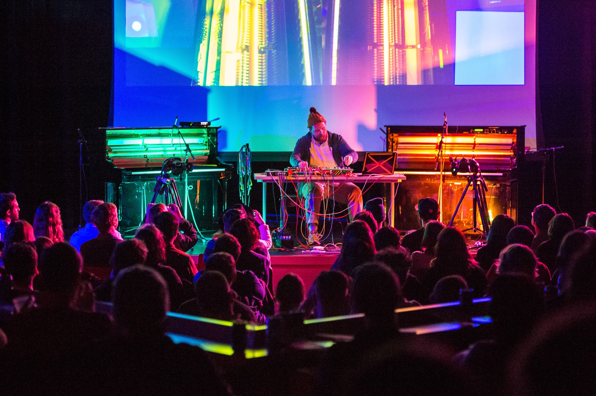 A DJ plays for a crowd surrounded by rainbow lights at the Exploratorium's After Dark event.