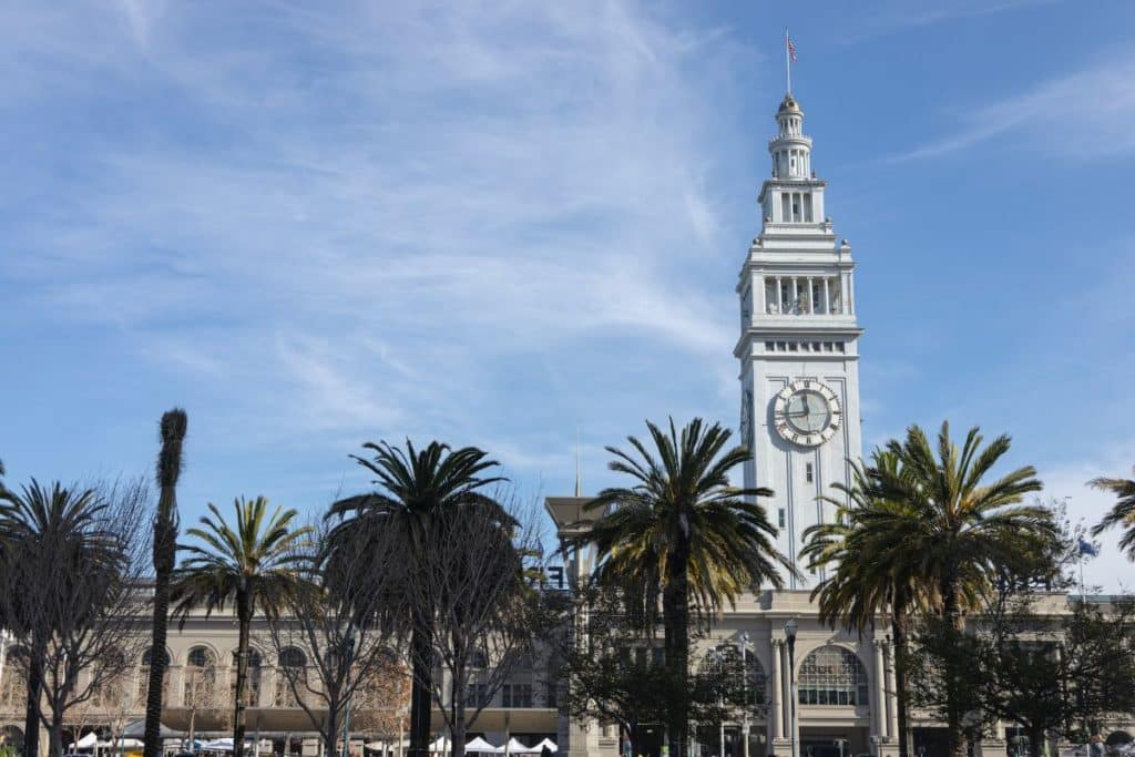 SF's Ferry Building clock tower flanked by palm trees.