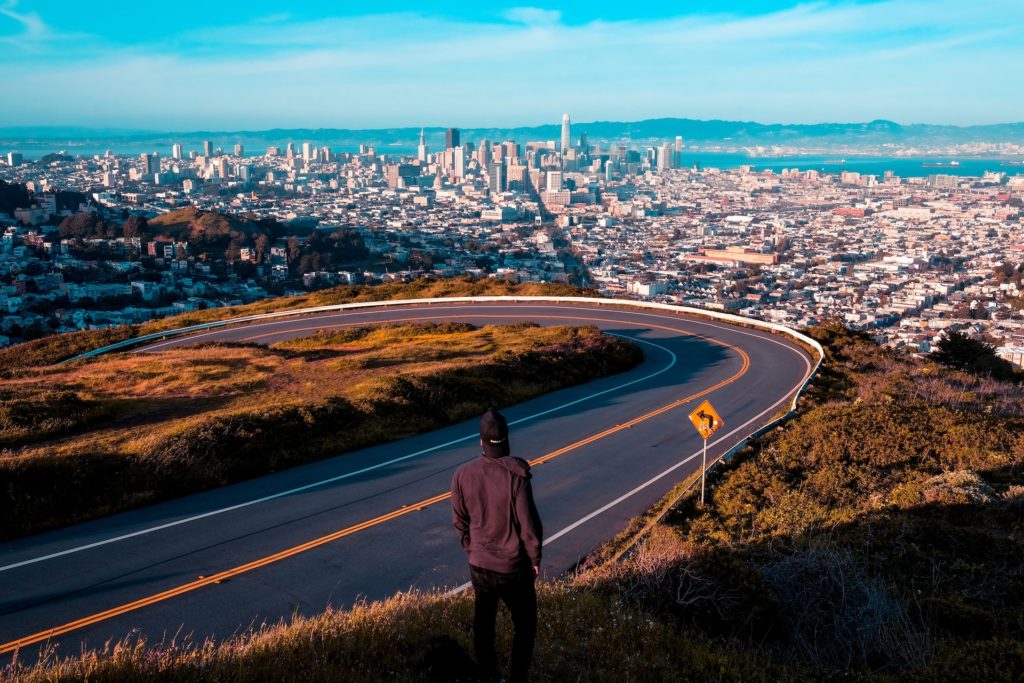 A man stands at Twin Peaks looking over the SF skyline.