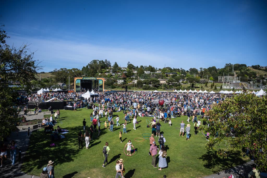 Hundreds of people gather in front of an outdoor stage at the Mill Valley Music Festival.