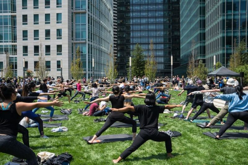 A group of people does yoga at Salesforce Park.
