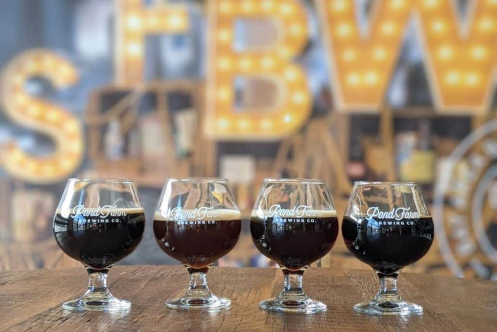 A flight of four dark beers lined up in front of luminous letters 