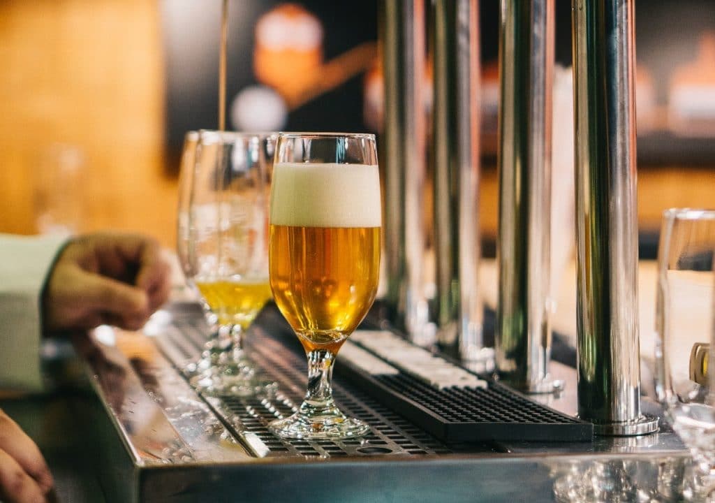 A bartender fills two glasses of beer.