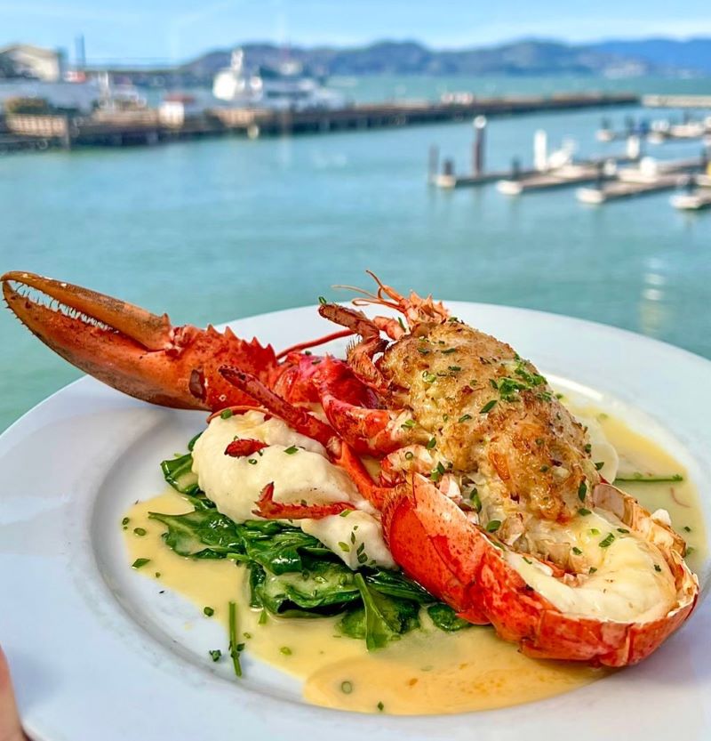 A plate of lobster stuffed with crab with the harbor view in the background.
