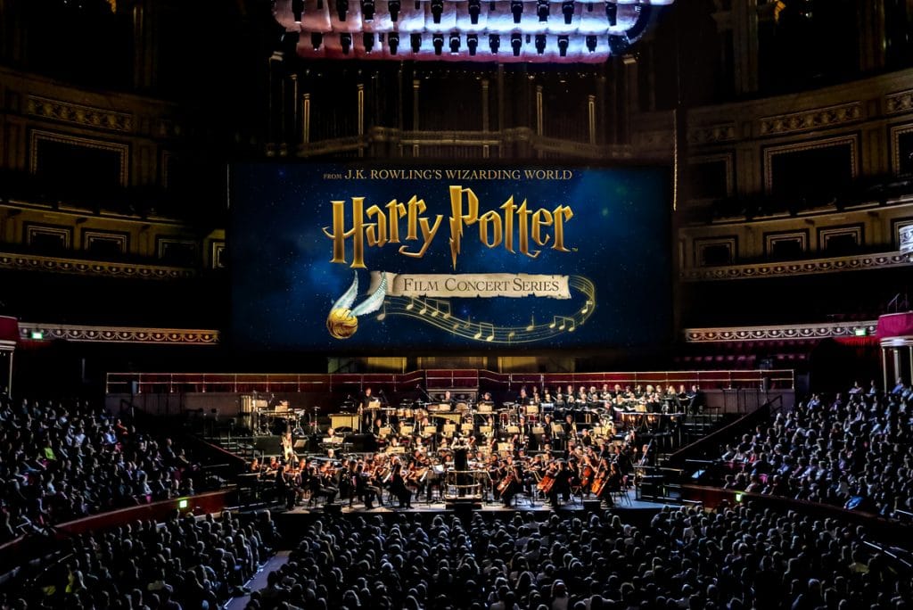 Harry Potter in Concert, featuring a large screen with Harry Potter titles and an orchestra beneath it.