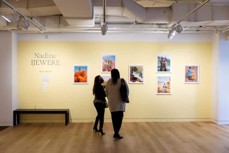 Two people look at a gallery wall titled "Nadine Ijewere"