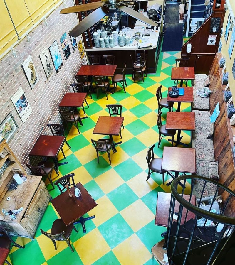 Zazie's dining room from above showing small wooden tables and a red and green checkered floor.