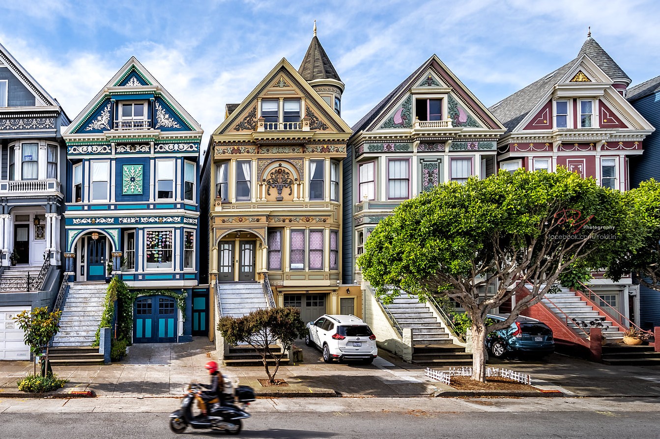 SF's Four Seasons Victorian homes in a line before a blue sky.