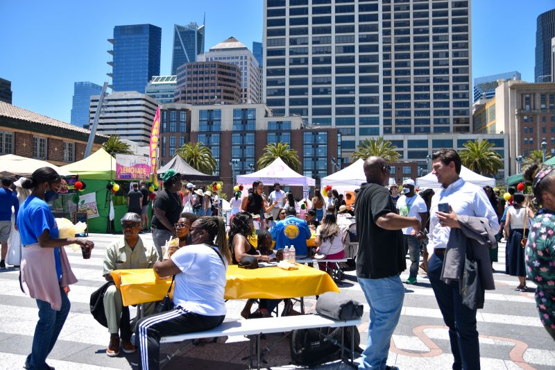 People gather at a table and market stalls at Juneteenth on the Waterfront