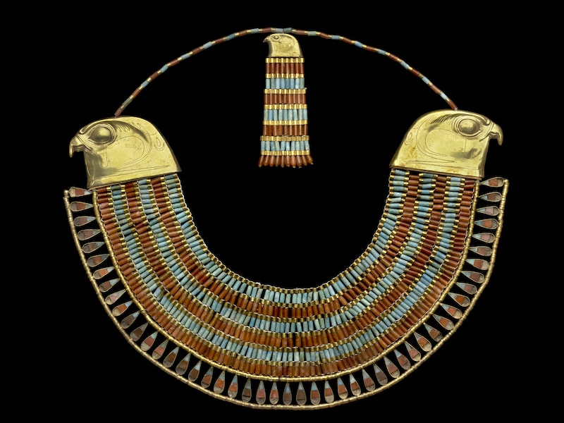 collar of Princess Neferuptah-The Egyptians called this form of collar the wesekh, meaning broad. Six rows of beads terminate with the head of a golden falcon at each end; these were used as fasteners. Two smaller chains of beads are attached to the falcons, leading to a counterpoise, which also bears the image of a falcon, with further horizontal rows of beads hanging from it. At the bottom of the collar, teardrop shaped pendants can be seen, connected to a row of small golden beads.
