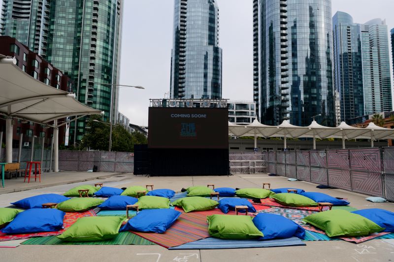 The Cut's outdoor cinema setup, featuring blue and green bean bag chairs in front of a jumbo outdoor LED screen with downtown skyscrapers in the background. 