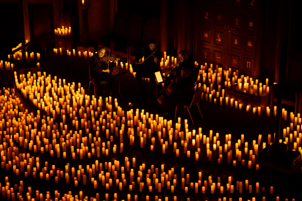 A string quartet is surrounded by candlelight