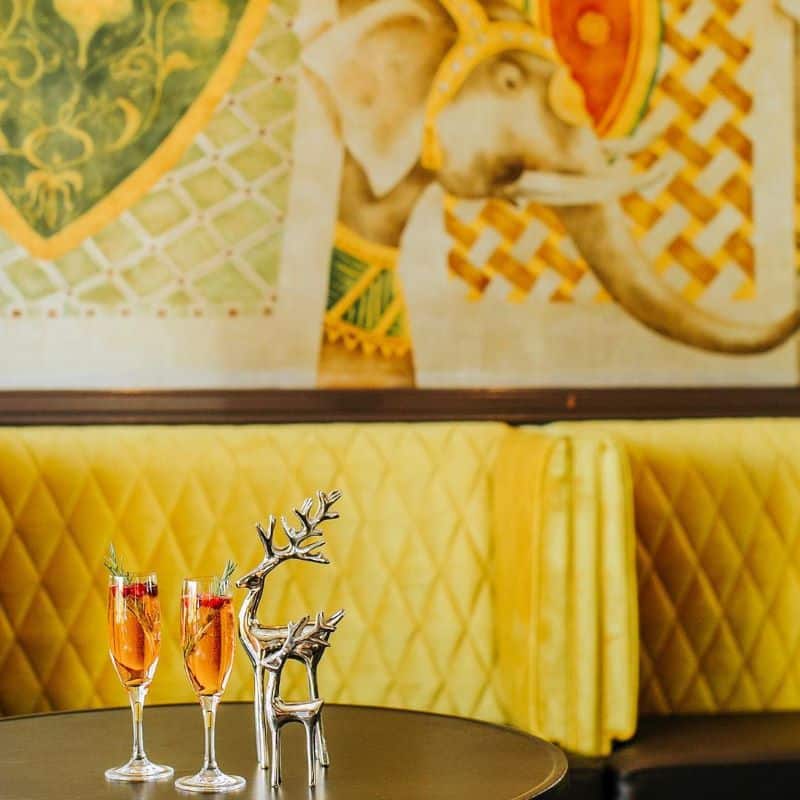 Two champagne flutes and a reindeer decoration on a table at Fairmont SF's Cirque bar