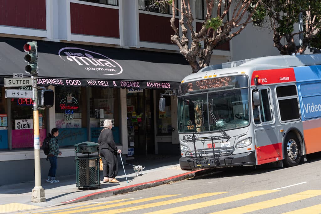 Bus pulling up to street corner in SF