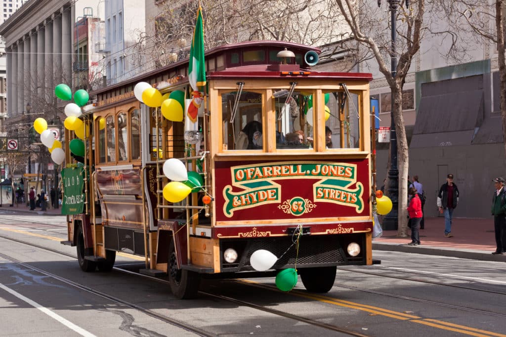An SF cable car decorated with green, yellow, and white balloons for ST Patricks Day.