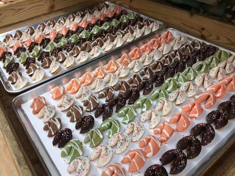 Rows of colored fortune cookies in chocolate, strawberry, vanilla, and green tea flavors.