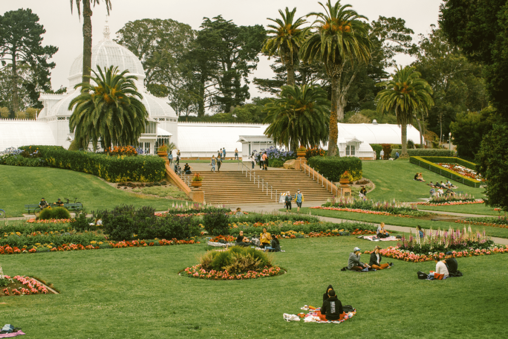 People lounge on the grass in front of the Conservatory of Flowers at Golden Gate Park.