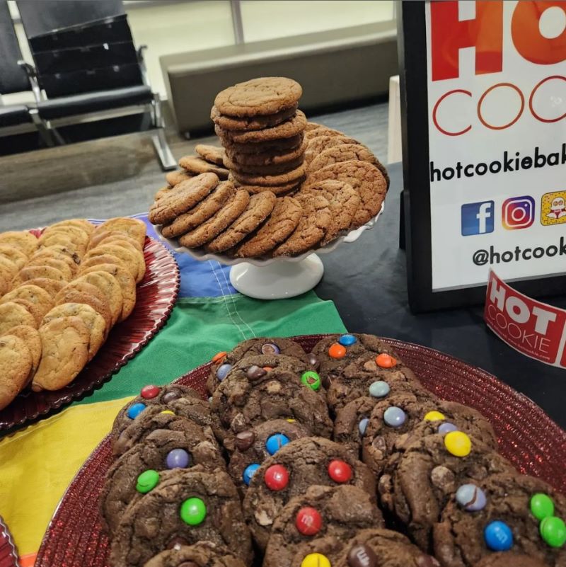 A display of rainbow M&M chocolate cookie, and chocolate chip cookies on a table.