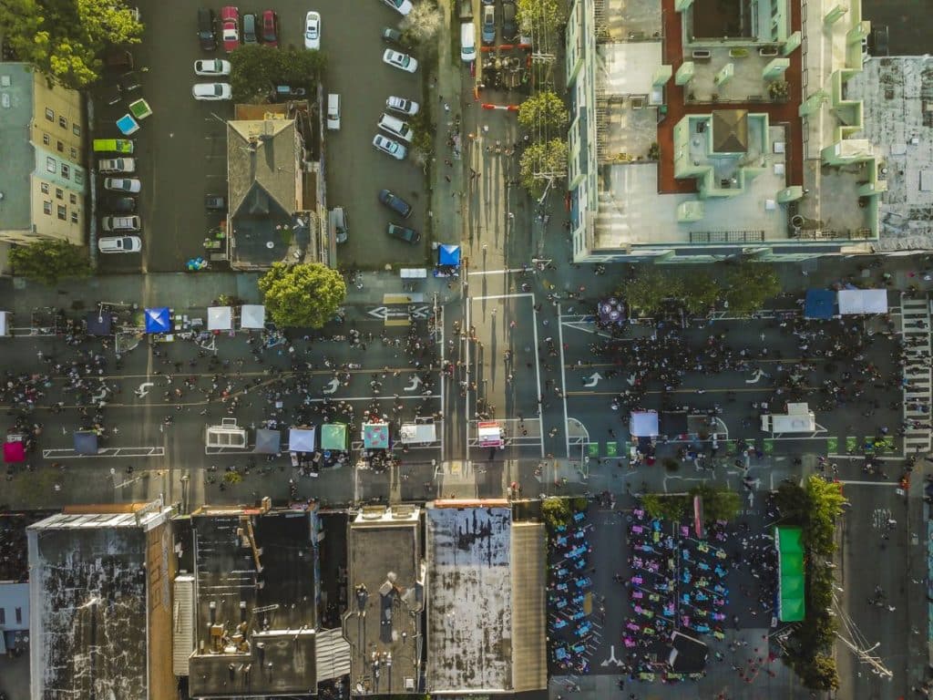 A birds-eye view of a busy city street with food trucks and vendors at Oakland First Fridays.