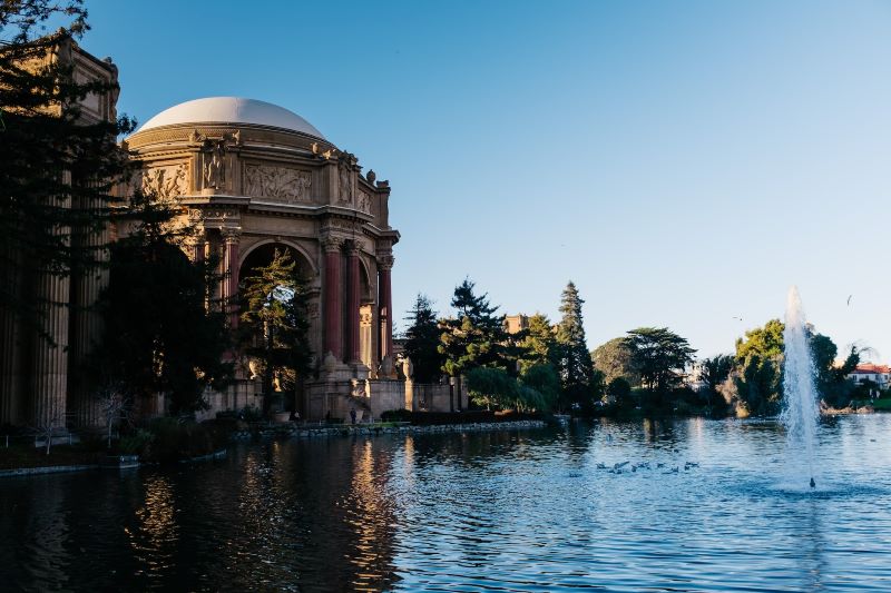 The Palace of Fine Arts beside a lake with a fountain in it.