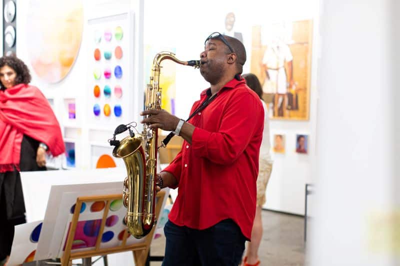 A man plays saxophone in an art gallery.