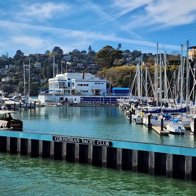Dozens of sailboats docked in the Tiburon harbor with a sign reading 'Corinthian Yacht Club' 
