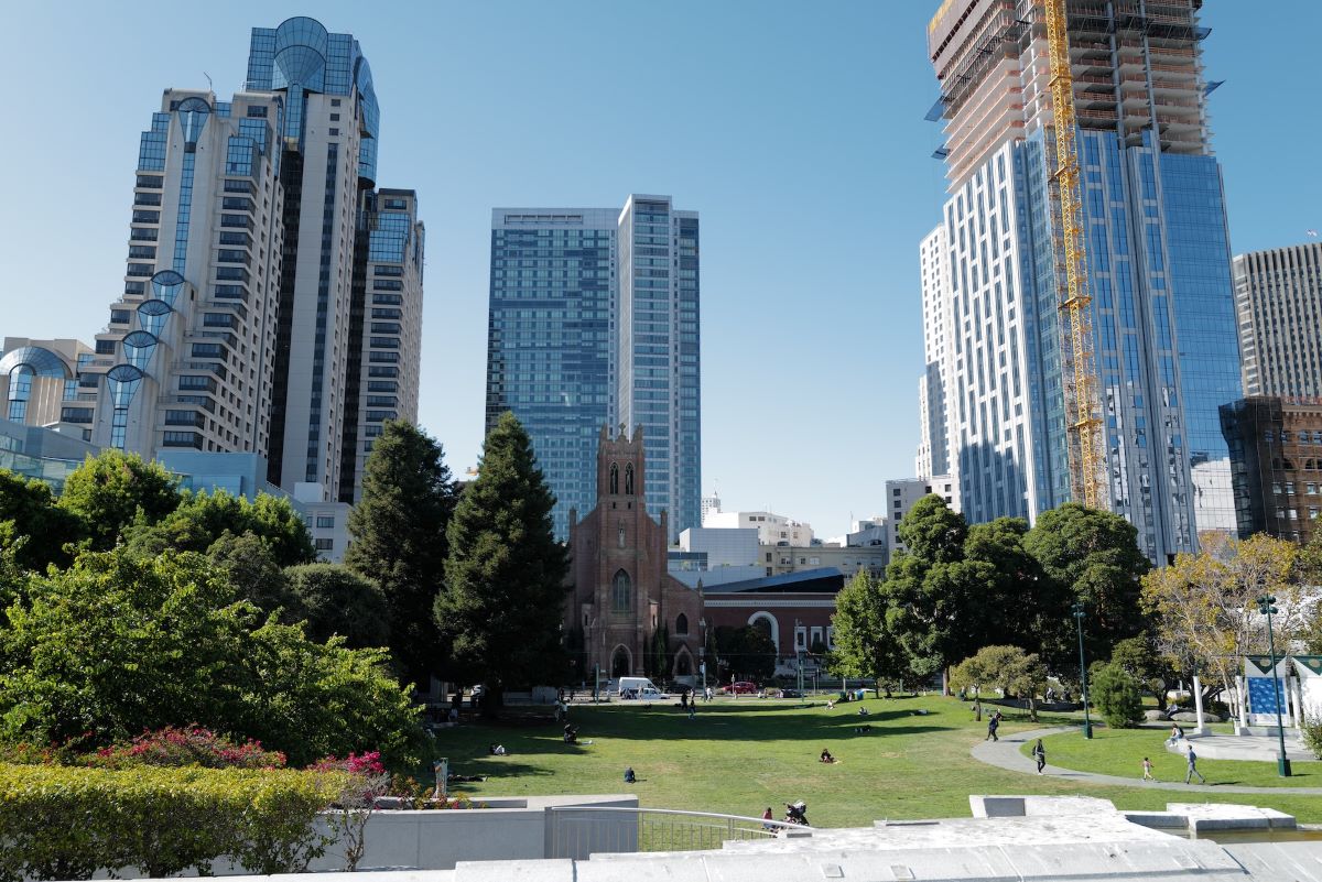 A green field surrounded by trees and skyscrapers at Yerba Buena Gardens.