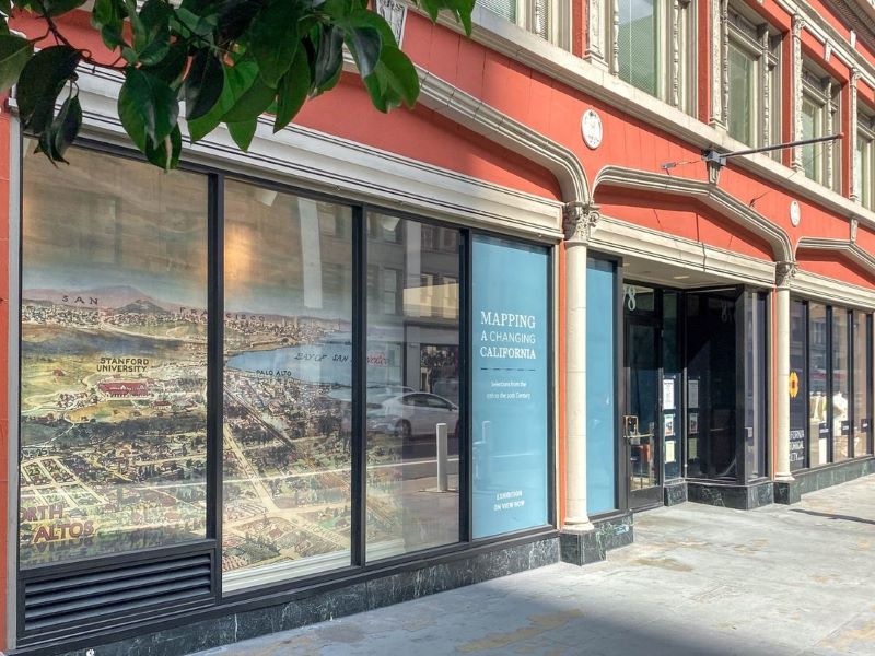 Exterior of CA Historical Society with a large map in the windows and a sign reading "Mapping a Changing California"
