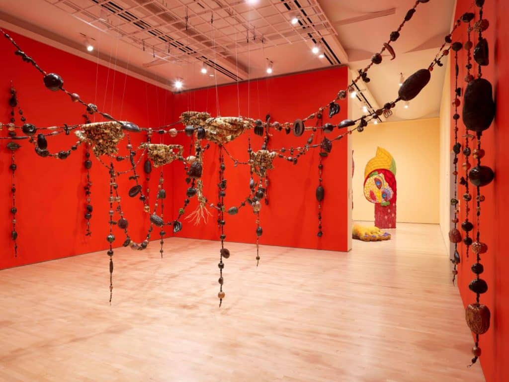 A red room with large beaded rocky garlands strung across and throughout the space.