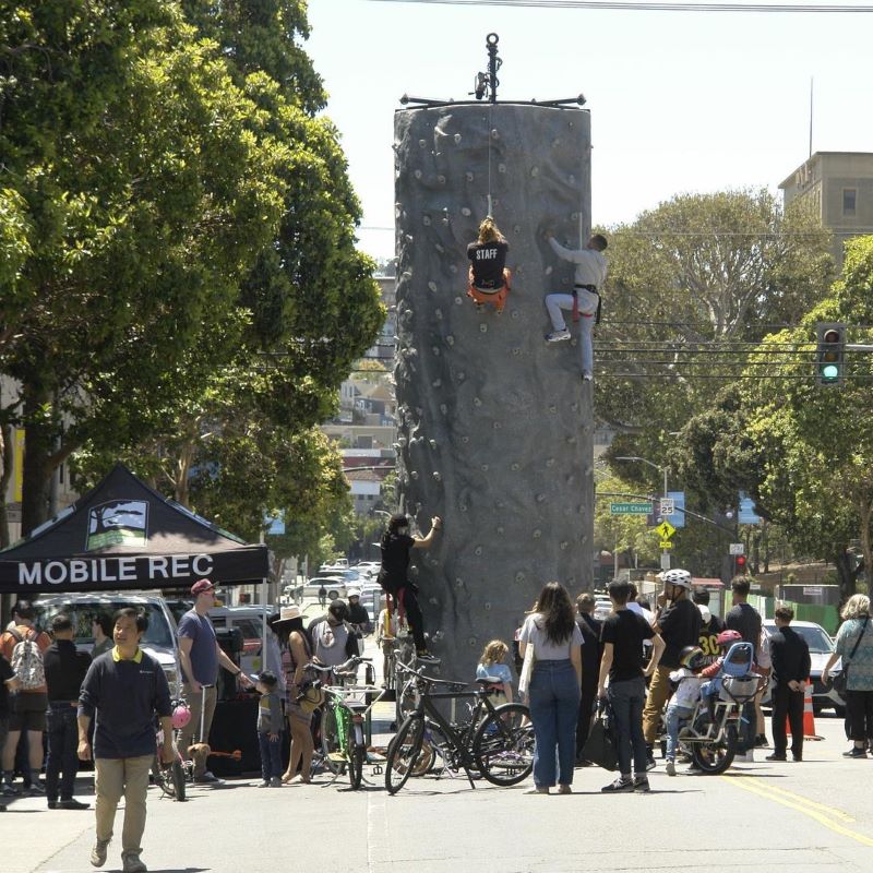 People climb a temporary rock-climbing wall at Sunday Streets SF