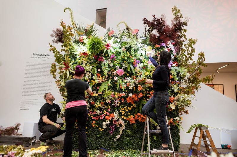 People arrange a large flower display at the de Young Museum.