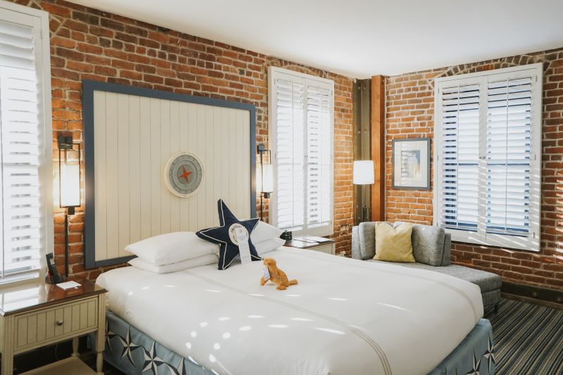 A nautical themed hotel room with brick walls and a star shaped pillow on the bed