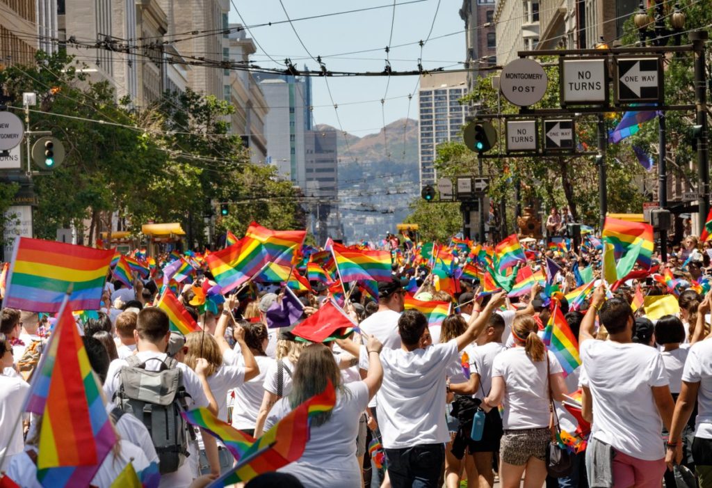 A crowd of people waves rainbow flags in San Francisco.