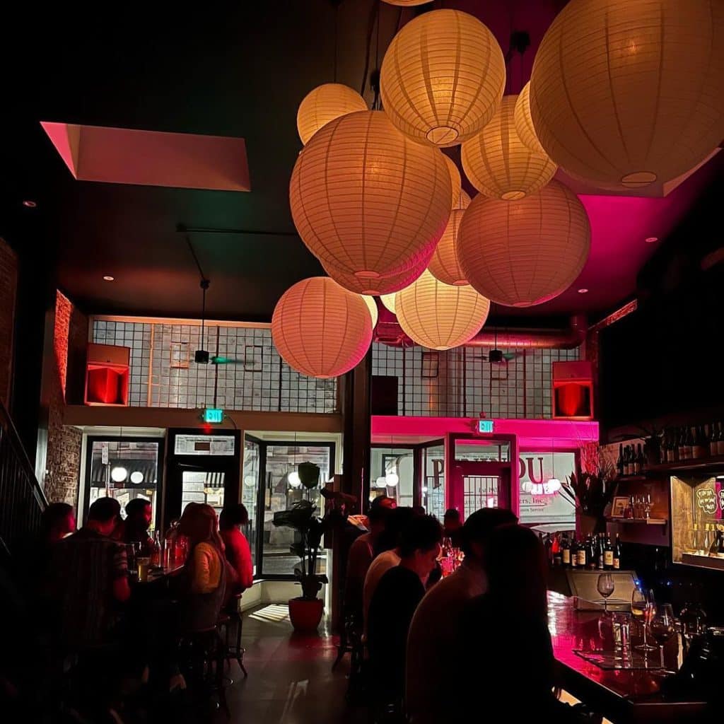 A crowded bar with large hanging lights.