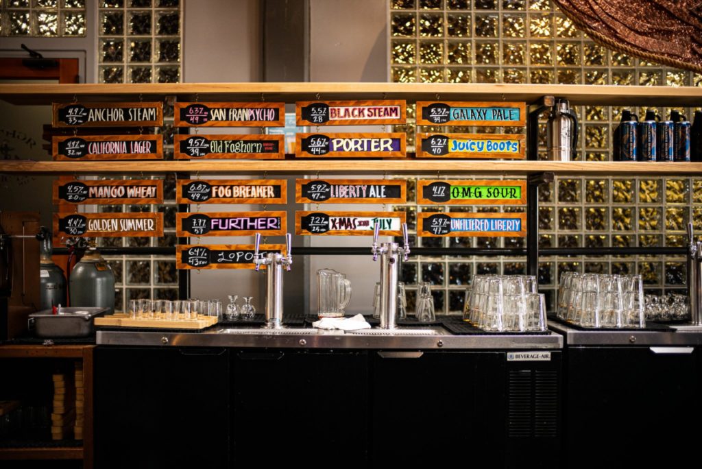 Bar with tap beer options listed behind it and a tap behind the counter.