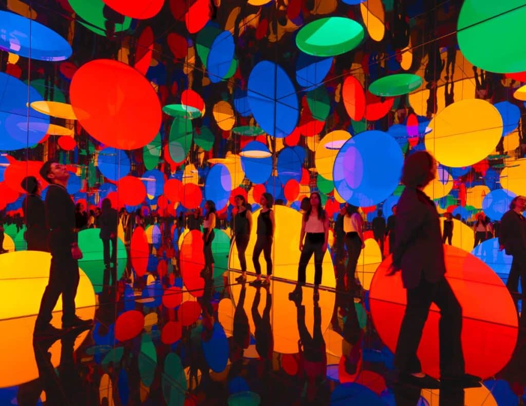 People stand in a mirror room covered in suspended colorful circles