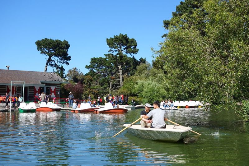 People row a boat near the boat house at Stow Lake on a sunny day in San Francisco