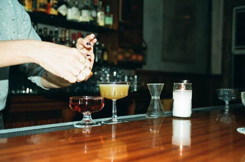 Close-up of a bartender making cocktails on a wooden bar.
