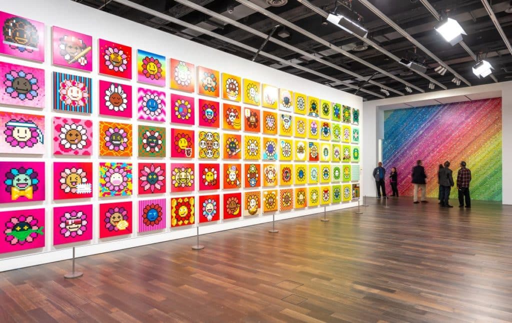 Red, pink, orange, and yellow graphic flower images arranged in a grid on a white gallery wall.