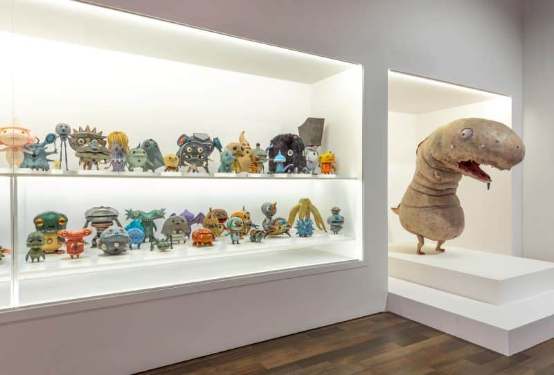 Two shelves filled with small colorful monster sculptures 