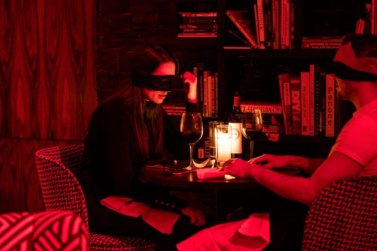 A woman sitting blindfolded at the Dining in the Dark experience.