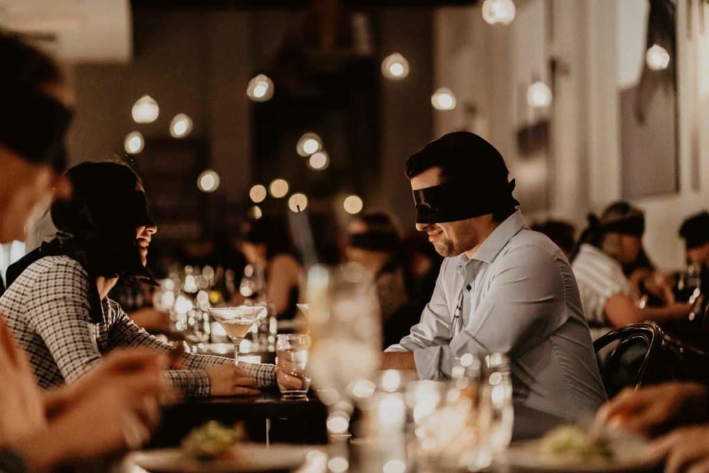A man sitting opposite his date at the Dining in the Dark experience.